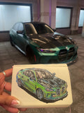 A hand holds a sketchbook featuring a Custom Car Portrait Commission of a green and black BMW, perfectly matching the real car parked behind it on a city street at night—an impressive piece of hand-drawn automotive art, making it an ideal gift for any car enthusiast.