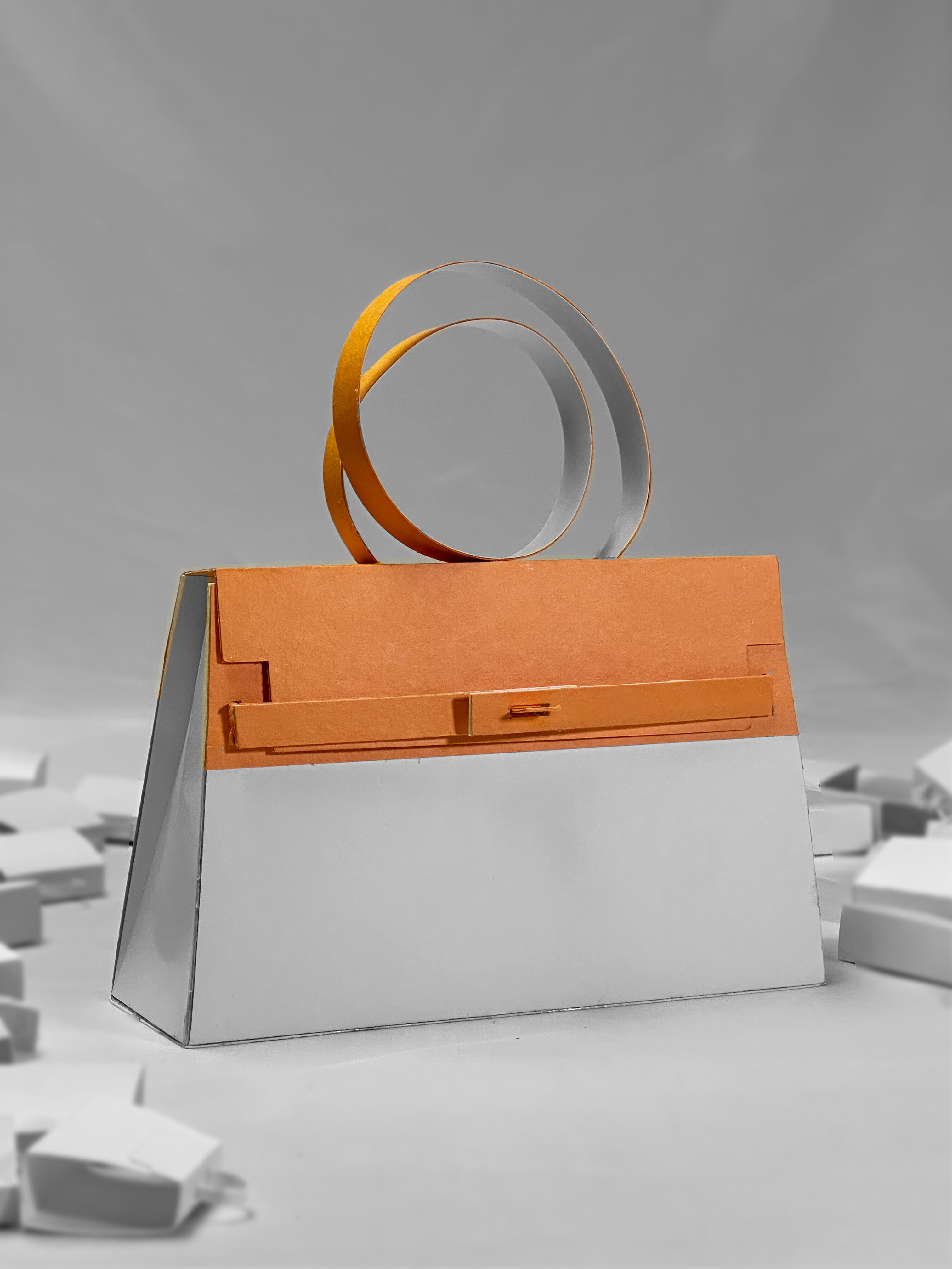 The Apricot Paper Purse is a stylish handbag with a geometric design, handcrafted from archival craft paper. It features a white body, orange flap, and two large circular handles, set against a soft gray background with white blocks.